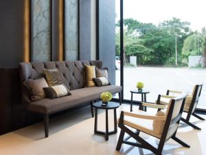 a couch and chairs in a room with a large window at Kesorn Boutique Hotel in Buriram