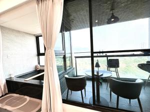 Habitación con ventana grande con sillas y mesa. en 拾月。頭城無邊際泳池溫泉房, en Toucheng