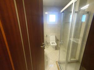 uma casa de banho com um WC e uma porta de vidro em Terminal Inn Airport Hotel & Apartment em Doha