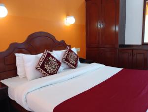a bedroom with a large bed with red and white pillows at Vedantha Inn in Kovalam