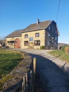 een groot bakstenen huis met een hek naast een weg bij La Cour de Grandmenil in Manhay
