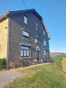 ein Backsteinhaus mit Tischen und Stühlen davor in der Unterkunft La Cour de Grandmenil in Manhay