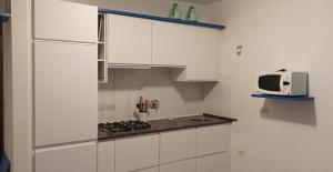 a small kitchen with white cabinets and a microwave at Gli Oleandri in Capoliveri