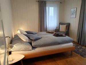 ein Schlafzimmer mit einem Bett mit Kissen und einem Stuhl in der Unterkunft Bed n Bureau Roggwil in Roggwil