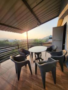 een patio met een tafel en stoelen op een balkon bij THE PERFECT STAYS : TRANQUIL VILLA in Lonavala