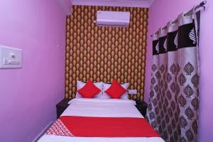 a small bedroom with a bed with red pillows at Flagship Hotel Magadh Empire in Patna