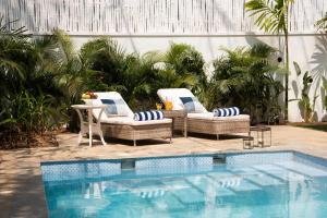uma piscina com duas cadeiras de vime e uma mesa ao lado de uma piscina em LohonoStays Villa Monforte B em Mapuçá