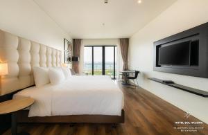 1 dormitorio con 1 cama blanca grande y TV de pantalla plana en Hotel Soleil Ha Long, Trademark Collection by Wyndham en Ha Long