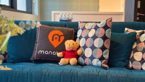 a teddy bear sitting on a blue couch with pillows at Manatidur@THE HUB SS2 in Petaling Jaya