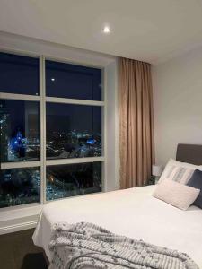 een slaapkamer met een groot raam met uitzicht op de stad bij Exclusive Suite CBD Riverviews - ParkingOnsite in Melbourne