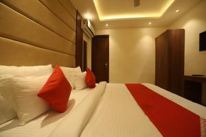 - une chambre avec un lit doté d'oreillers rouges et blancs dans l'établissement Super OYO Status Inn, à Dehradun