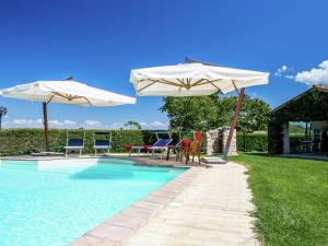 - une piscine avec deux parasols, des chaises, une table et des chaises dans l'établissement Inviting cottage in Marsciano with private terrace, à Marsciano