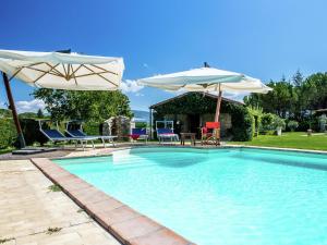 - une piscine avec 2 parasols, une table et des chaises dans l'établissement Inviting cottage in Marsciano with private terrace, à Marsciano