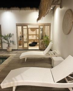 a living room with two white chairs and a mirror at Mimpi Villa - Gili Air in Gili Air