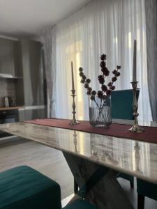 a table with two candles and a vase with flowers on it at Noa Residence in Alba Iulia