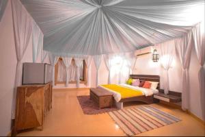 Luxury The Sunrise Resort with swimming pool Jaisalmer في جيلسامر: غرفة نوم مع خيمة مع سرير وتلفزيون