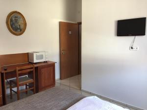 a bedroom with a bed and a desk with a microwave at Lamar Apartman in Kapuvár