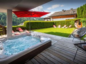 a hot tub on a wooden deck with an umbrella at Chalet Alyssum - OVO Network in Le Grand-Bornand