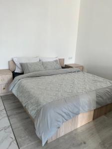 een witte slaapkamer met een groot bed met grijze lakens bij New Marine Apartment in Yuzhne