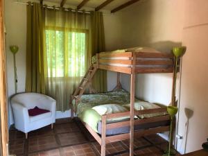 a bunk bed in a room with a chair and a window at Chambre d'hôtes de Paille et d'Argile in Touligny