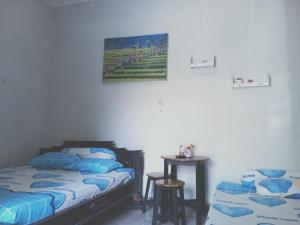 a bedroom with two beds and a table in it at Kost Backpacker in Sidoarjo