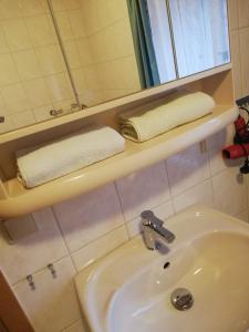 a bathroom with a sink and a mirror and towels at Gästezimmer an der Loipe in Bienenmühle