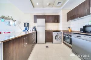 a kitchen with wooden cabinets and a washer and dryer at Contemporary One Bedroom with Full Marina View in Dubai