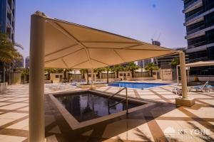 a pool with a large umbrella on a building at Contemporary One Bedroom with Full Marina View in Dubai