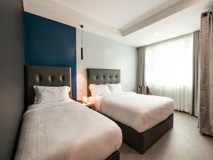 duas camas sentadas uma ao lado da outra num quarto em Homes at Bay Area Suites by SMS Hospitality em Manila