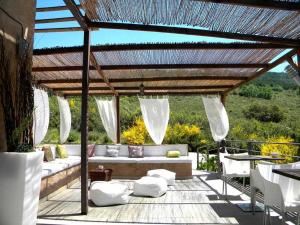 un patio con sofá y sillas bajo una pérgola en El Refugio de Cristal en Hontanar