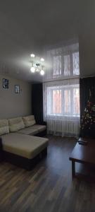 a living room with a couch and a christmas tree at 5 мин международный аэропорт in Prigorodnyy