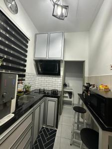a kitchen with white cabinets and a black counter top at MK Homestay Perlis in Arau