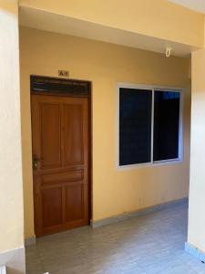 ein leeres Zimmer mit einer Tür und einem Fenster in der Unterkunft Qarib Rock City in Mwanza