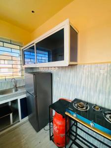 a kitchen with a black counter and a refrigerator at Qarib Rock City in Mwanza