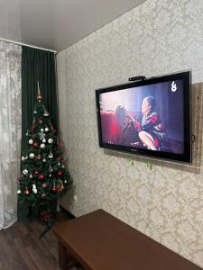 a living room with a christmas tree and a flat screen tv at 5 мин международный аэропорт in Prigorodnyy