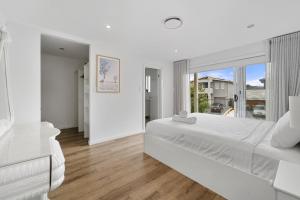 um quarto branco com uma cama grande e uma janela em Spacious 5 Bedroom 2.5 bathroom House in Gregory Hills em Narellan