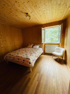 a bedroom with a bed and a chair and a window at Chalet Barcelonnette - location saisonnière in Barcelonnette