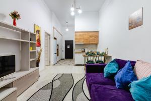 sala de estar con sofá púrpura y cocina en 2 комнатная квартира в сердце города - цокольный этаж en Almaty