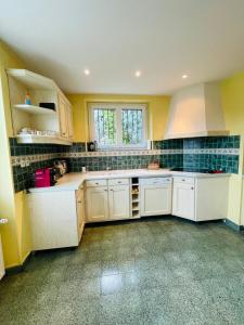a kitchen with white cabinets and green tiles on the walls at Chalet Barcelonnette - location saisonnière in Barcelonnette