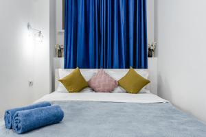 1 cama con almohadas coloridas y cortina azul en 2 комнатная квартира в сердце города - цокольный этаж en Almaty