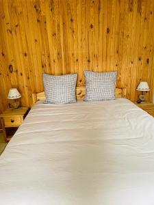 1 dormitorio con 1 cama blanca y paredes de madera en Chalet Barcelonnette - location saisonnière, en Barcelonnette