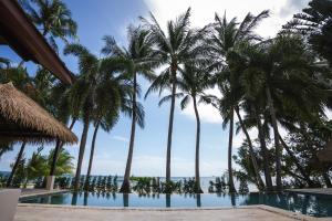 una piscina con palme e l'oceano sullo sfondo di Samahita Retreat a Laem Sor