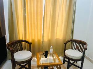 2 chaises et une table avec une bouteille d'eau sur une table dans l'établissement Hotel The Pacific Paradise, à Haridwar