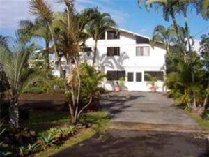 a white house with palm trees and a driveway at Hale-Hoola B & B in Captain Cook