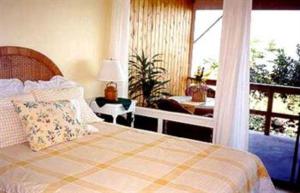 a bedroom with a bed and a desk and a window at Hale-Hoola B & B in Captain Cook