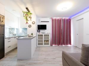 a kitchen with white cabinets and a tv in a room at 3D. Brand new flat in Playa Las Américas in Playa de las Americas