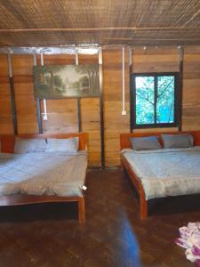 two beds in a room with wooden walls at Sok Phen Homestay in Siem Reap