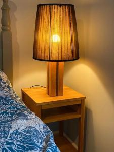 a lamp sitting on a table next to a bed at Bluebell Annexe in Little Grandsen