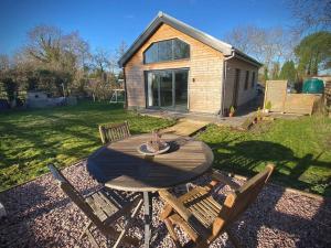a wooden table and two chairs in a yard at Bluebell Annexe in Little Grandsen