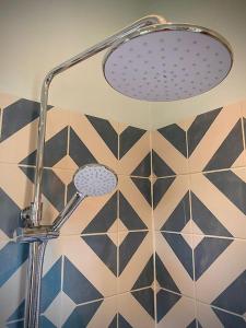 a shower head in a bathroom with a tiled wall at Bluebell Annexe in Little Grandsen